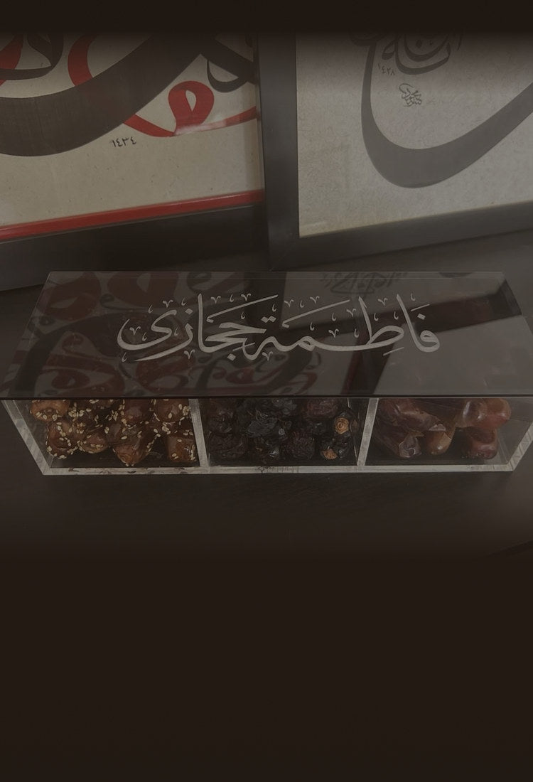 A personalised acrylic dates box with «فاطمة حجازي» engraved on the lid in Thuluth