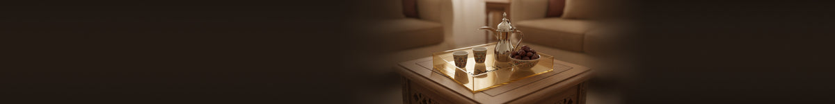 A gold-tinted acrylic serving tray engraved «دار السعادة», with a dallah, coffee cups and dates, on a carved wooden table