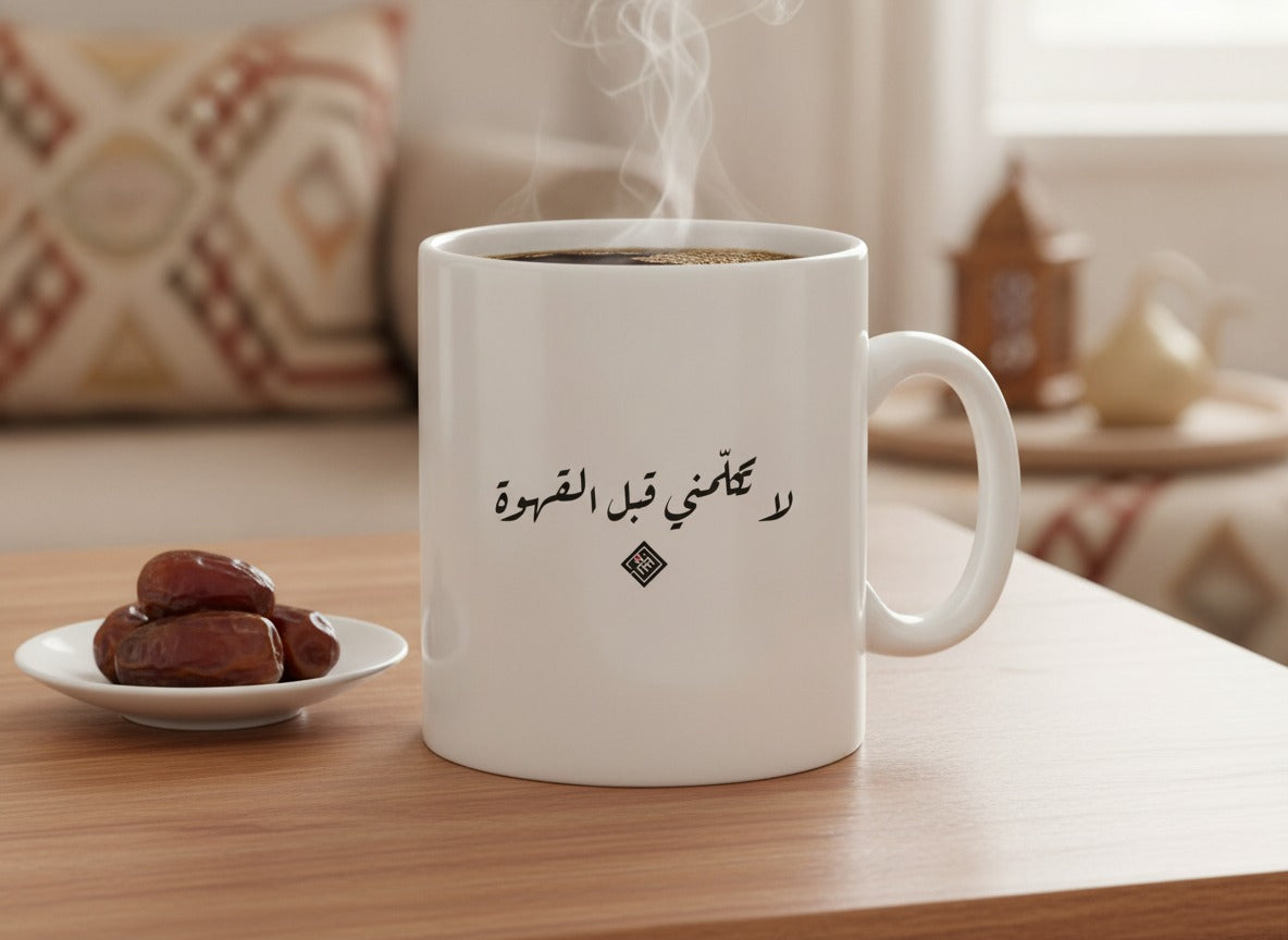 «لا تكلّمني قبل القهوة» كوب بخط الرقعة، ممتلئ، على طاولة قهوة