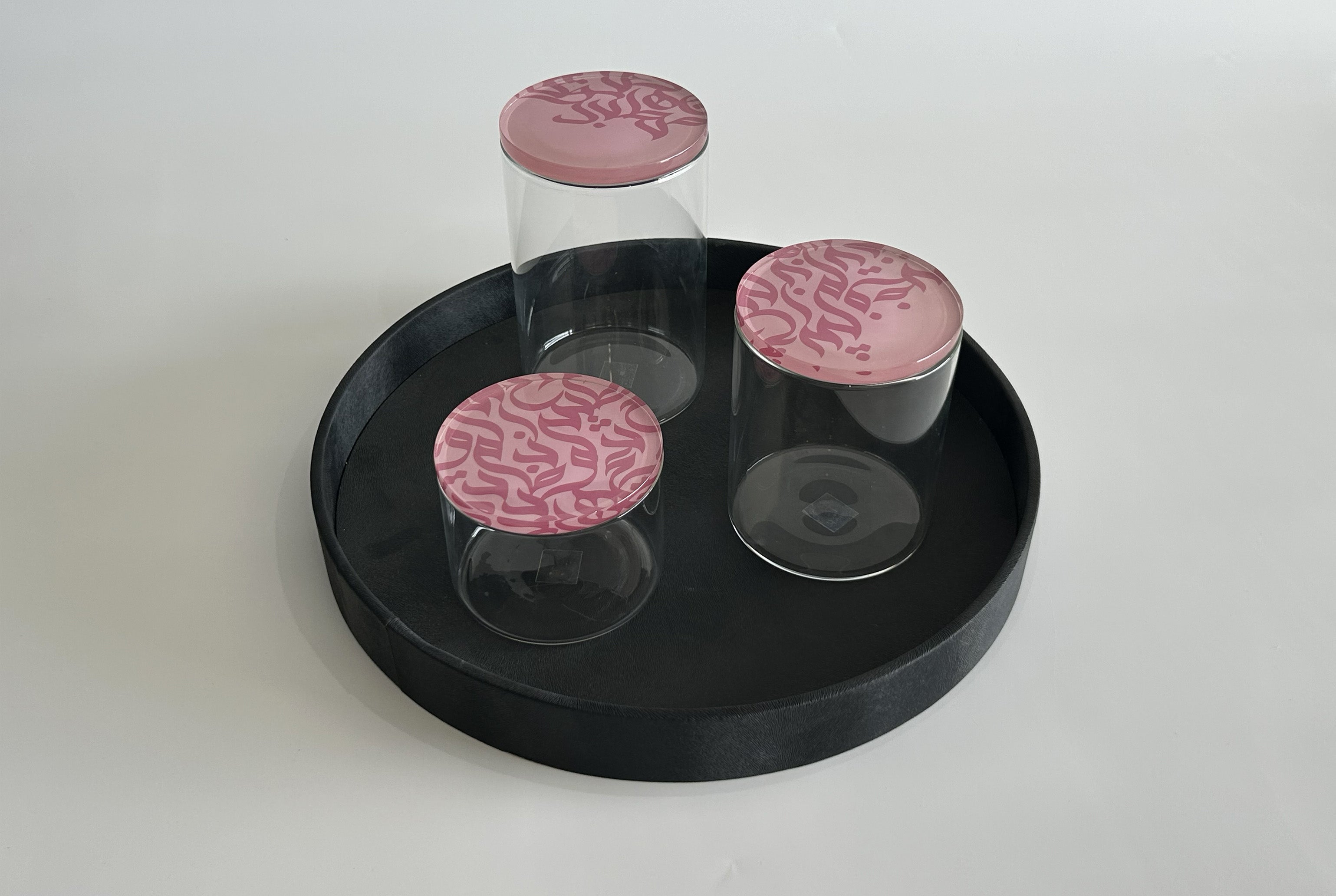 Glass jar set with Arabic calligraphy lids on a leather serving tray by MASHQ Dubai