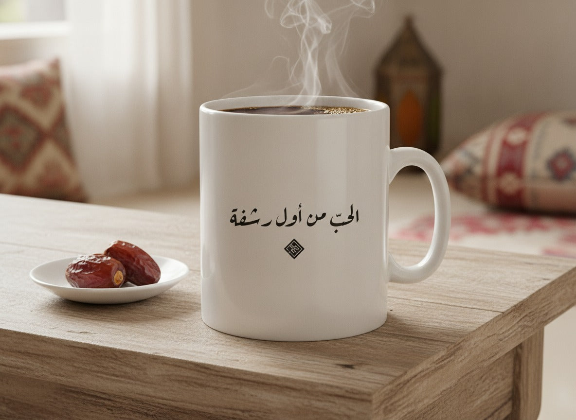 «الحبّ من أول رشفة» بخط الرقعة مطبوعة على كوب من السيراميك، مصوّر على طاولة