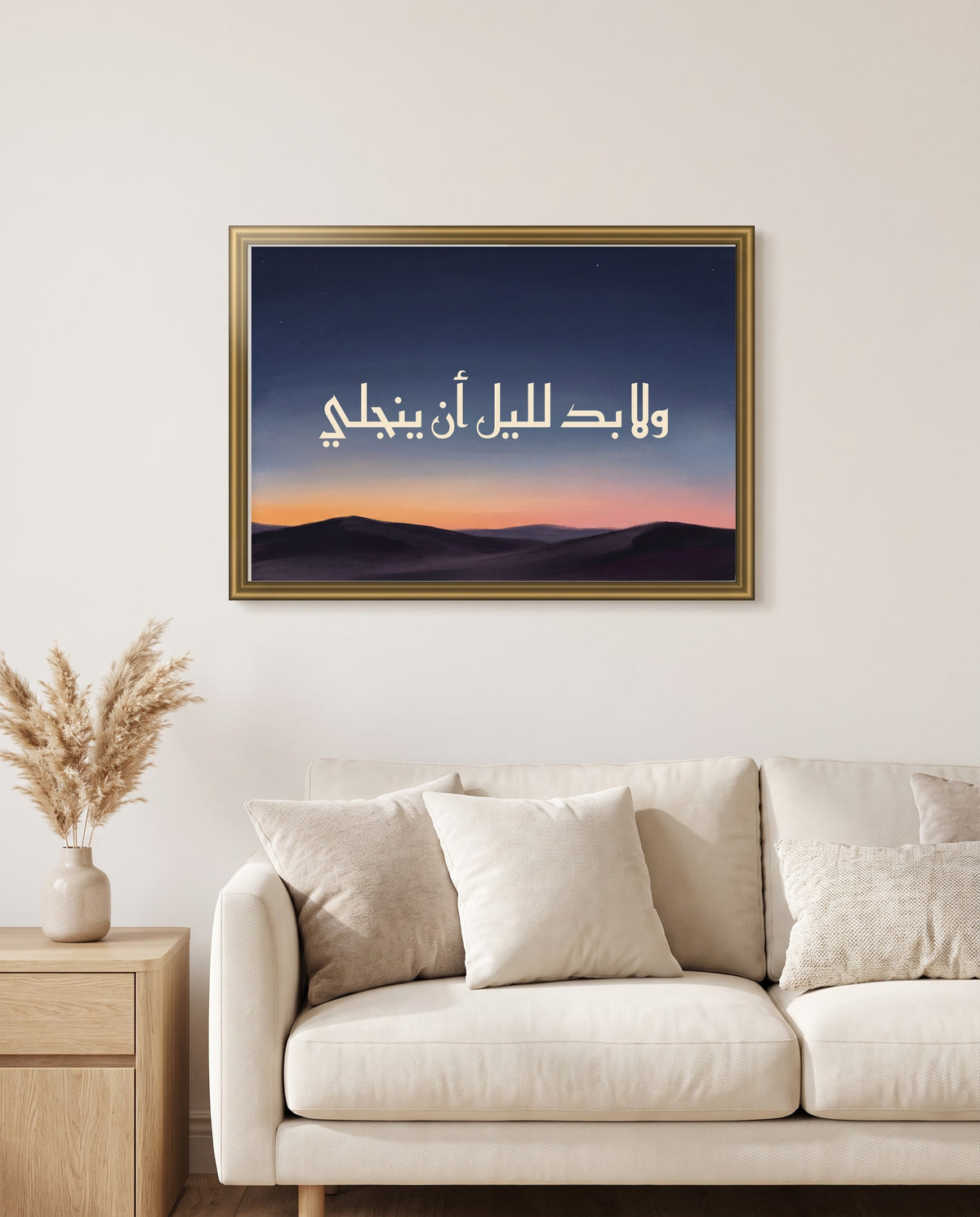 «ولا بد لليل أن ينجلي» بالخط الكوفي في إطار ذهبي مصقول فوق أريكة كريمية في غرفة الجلوس