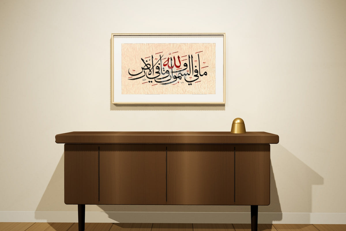 «لله ما في السموات وما في الأرض» by Ahmed Alhawary, 70 × 50 cm, shown to scale in a natural oak frame on a majlis wall — framing available on request