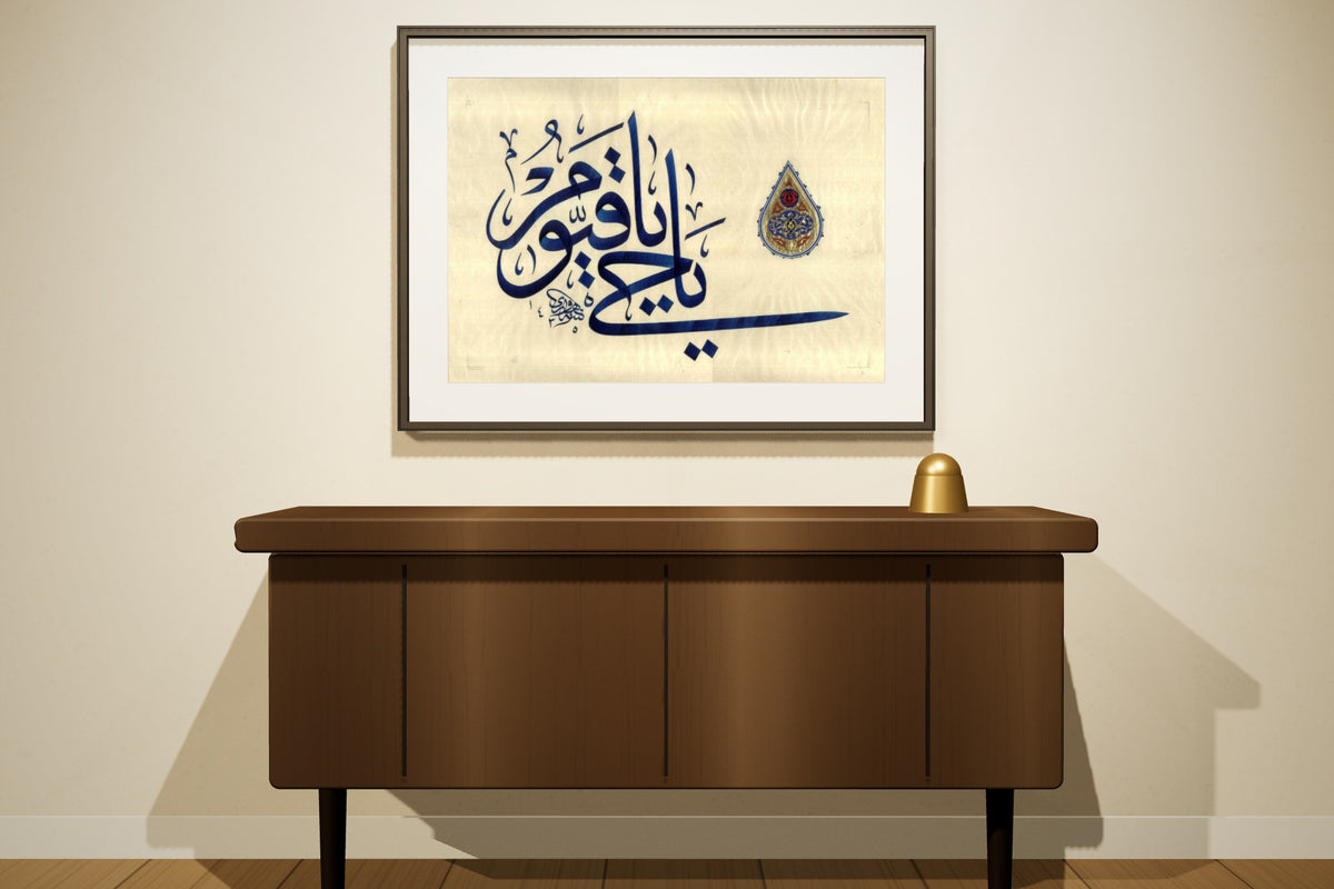 «يا حي يا قيوم» by Ahmed Alhawary, 90 × 60 cm, shown to scale in a slim black frame on a majlis wall — framing available on request