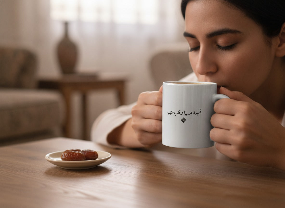 «قهوة عربية وقلب طيّب» calligraphy mug in hand, mid-sip